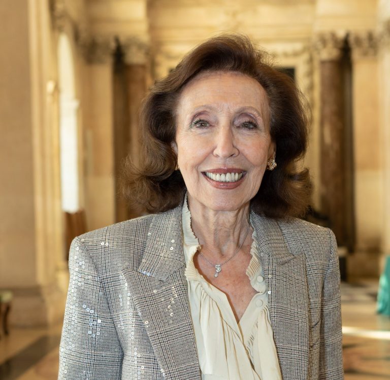 Portrait d’une femme âgée souriante dans un intérieur élégant et lumineux.