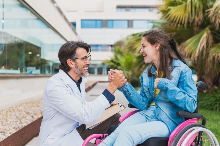 Médecin souriant échangeant avec une jeune femme en fauteuil roulant.