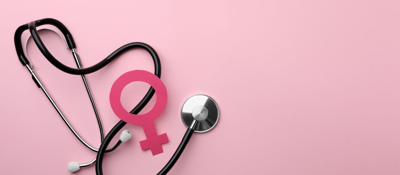 Stéthoscope et symbole féminin posés sur un fond rose.