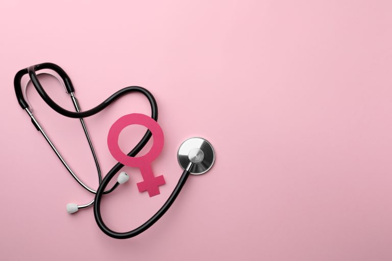 Stéthoscope et symbole féminin posés sur un fond rose.