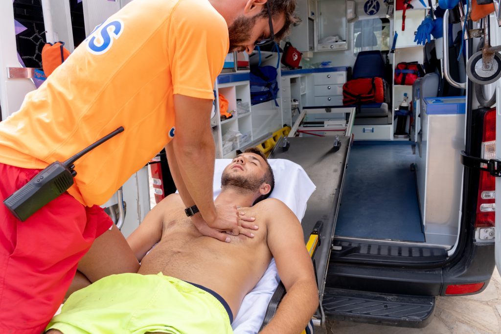 Un secouriste réalise un massage cardiaque sur une victime dans un véhicule du SAMU
