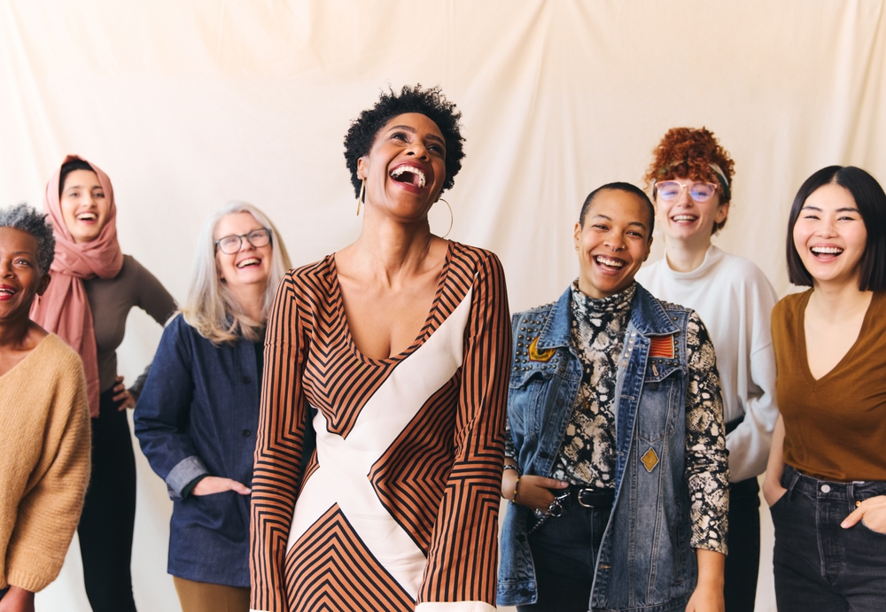 Un groupe de femmes de différentes origines rit ensemble dans une ambiance chaleureuse et conviviale.