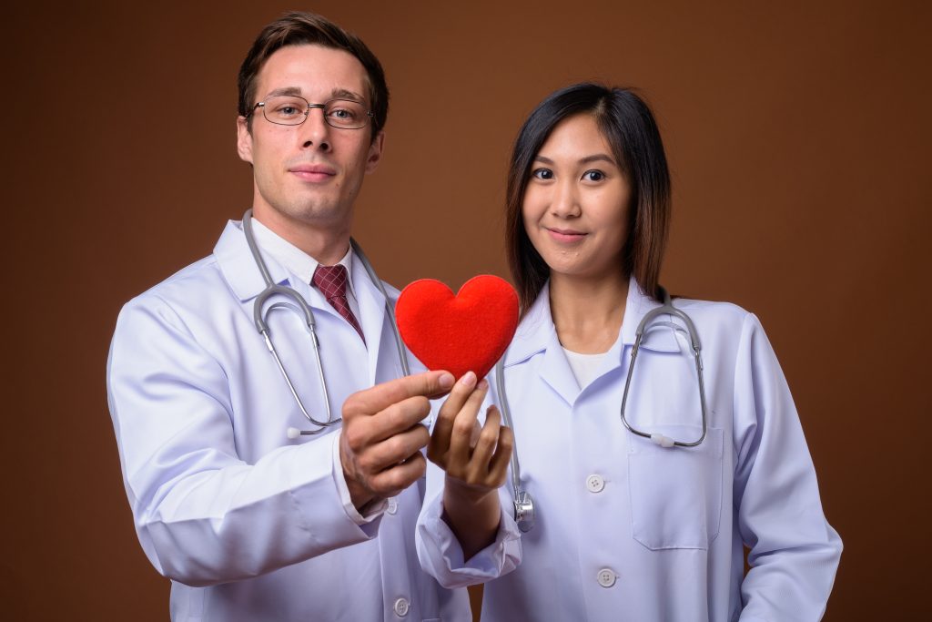 Deux professionnels de santé tiennent un cœur rouge symbolique.