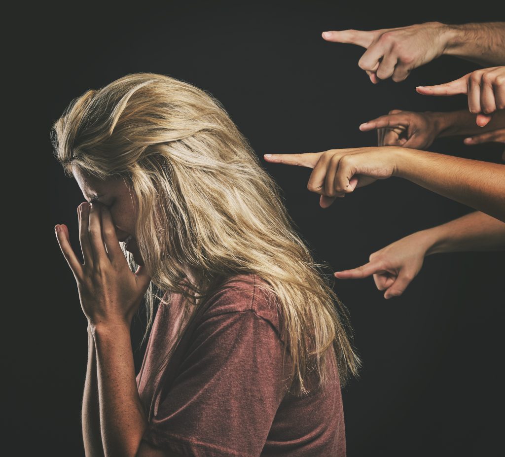 Femme en détresse pendant que plusieurs mains la pointent du doigt.